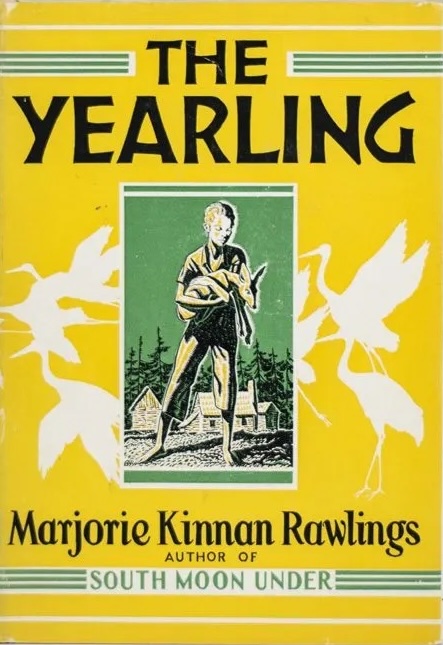The cover of the 1938 edition of The Yearling, a boy stands holding a deer