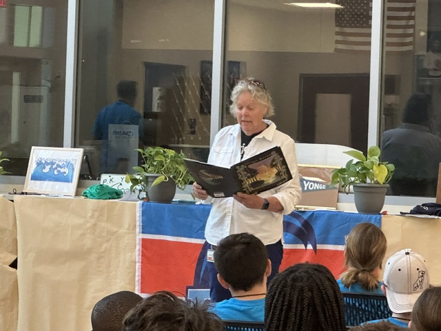 Flo Turcotte stands in front of children reading from The Secret River